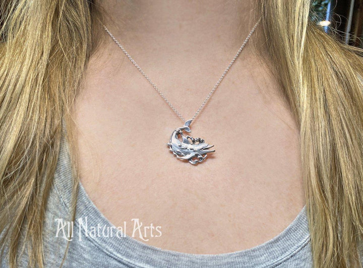 A girl wearing a sterling, silver dolphin, happily swimming with bubbles coming off his body on a sterling silver chain.