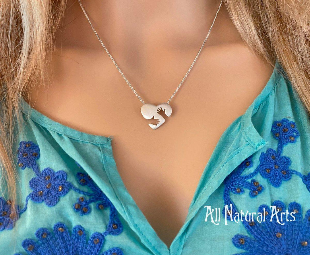 Close-up of the sterling silver Everlasting Hug pendant on silver chain on model.