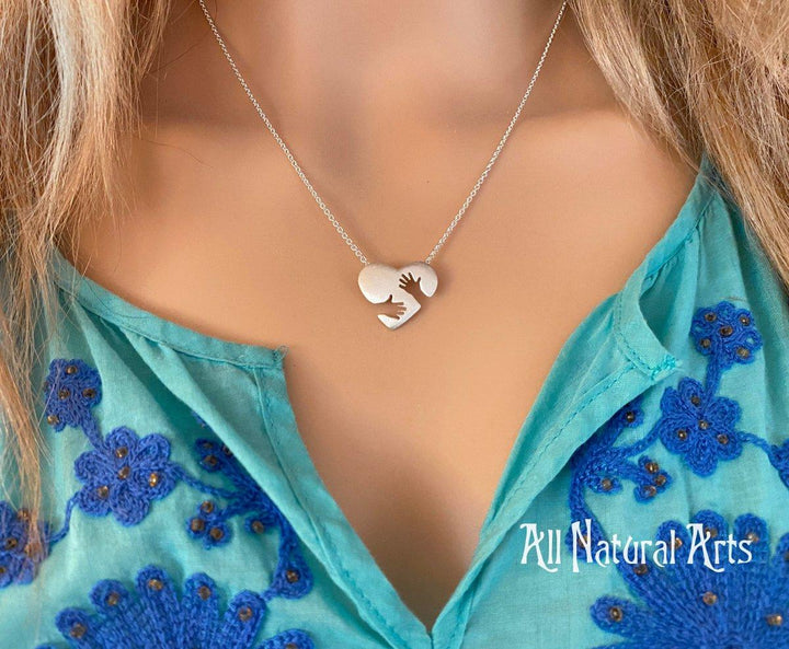 Close-up of the sterling silver Everlasting Hug pendant on silver chain on model.