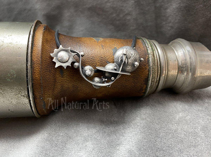 Silver Planets necklace draped over antique binoculars.