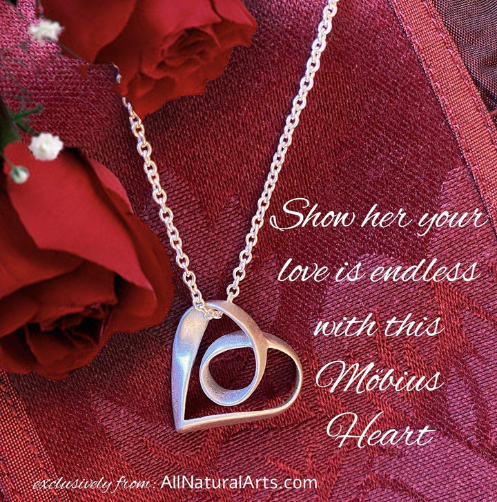 Sue Beatrice's Möbius Heart Pendant: Sterling silver necklace with infinite symbolism on red background.