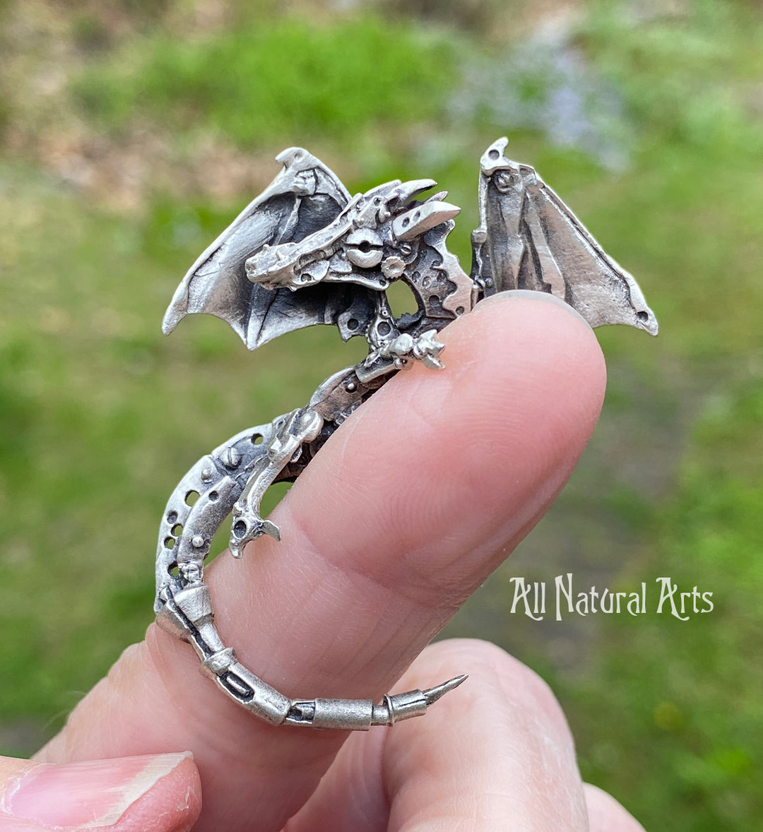 Sue Beatrice's silver finger dragon pendant perched on a finger.