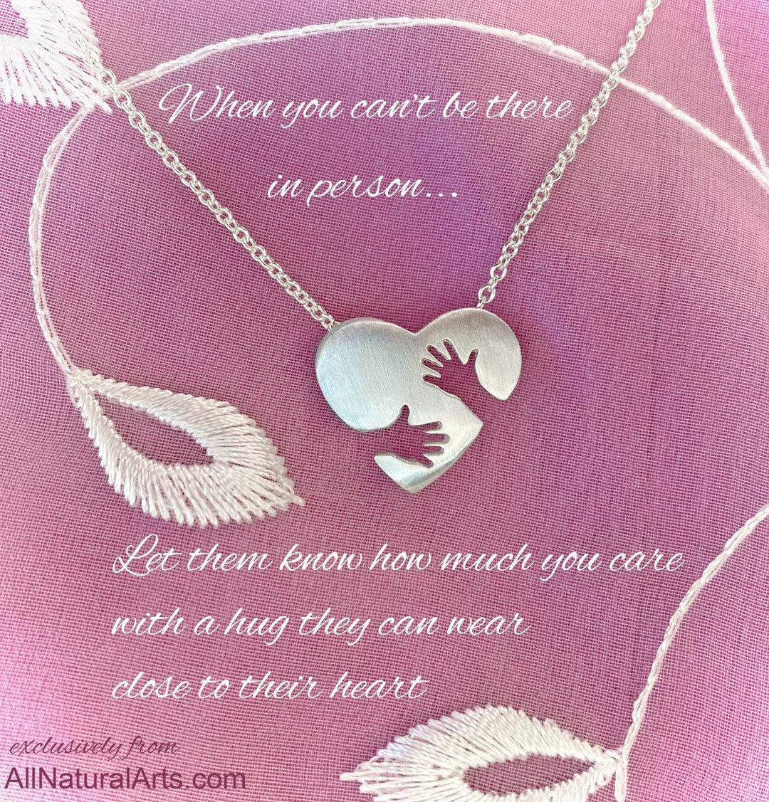 "Everlasting Hug pendant by Sue Beatrice: detailed sterling silver embrace symbolizing enduring love and support."