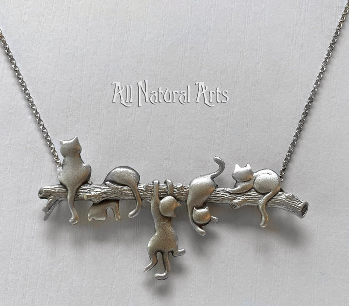 An endearing silver necklace with 5 playful cats on a branch. 