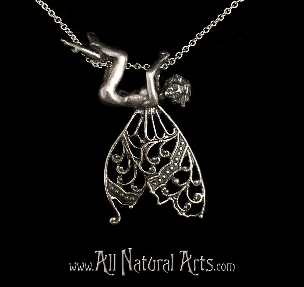 Silver sprite pendant playfully hangs from chain from her hands and legs."