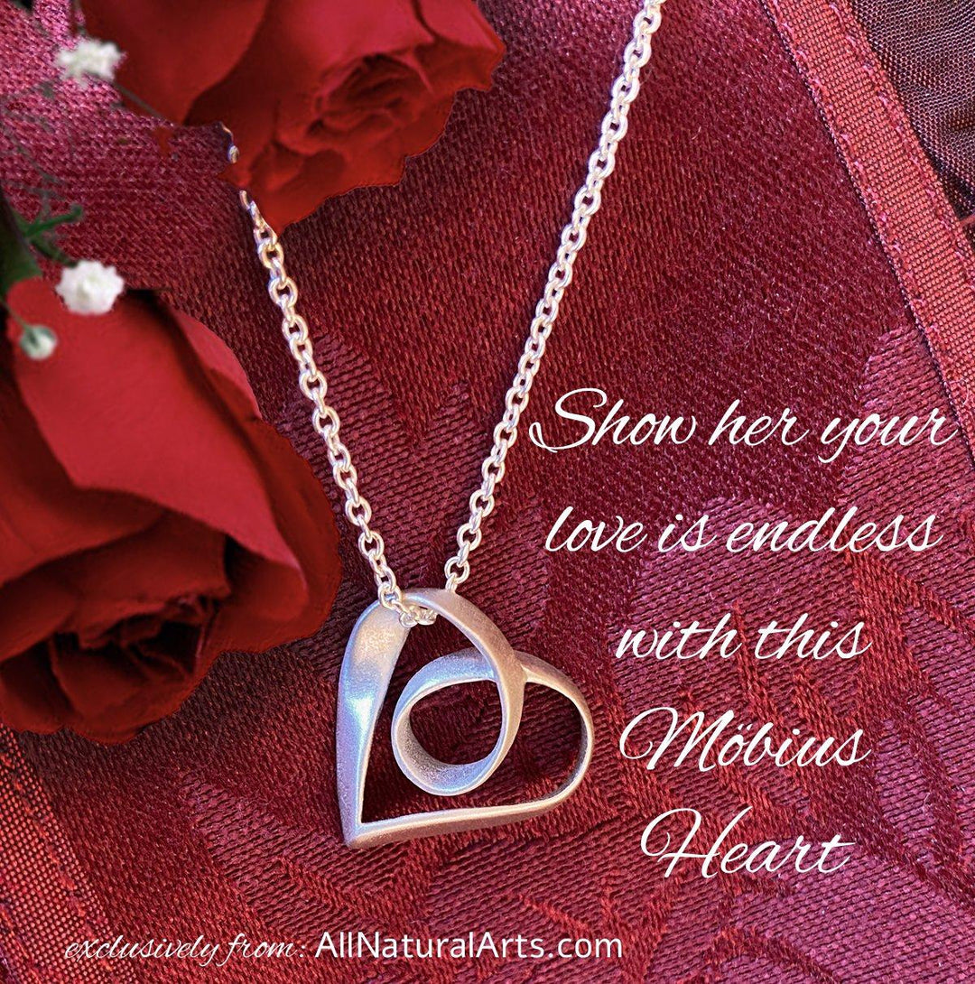 Sue Beatrice's Möbius Heart Pendant: Sterling silver necklace with infinite symbolism on red background. 