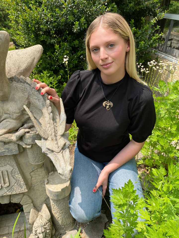 Girl next to concrete dradon wearing handmade 'Gotham' Dragon Pendant by Sue Beatrice, made from vintage pocket watch parts and cast in silicon bronze.