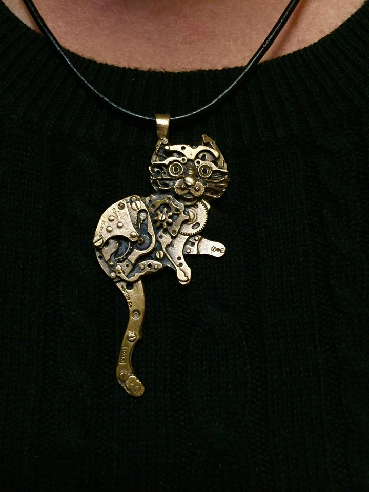 Close up photo of Watch Parts Kitty pendant made of silicon bronze, designed by Sue Beatrice of All Natural Arts, featuring intricate details of antique watch parts. 
